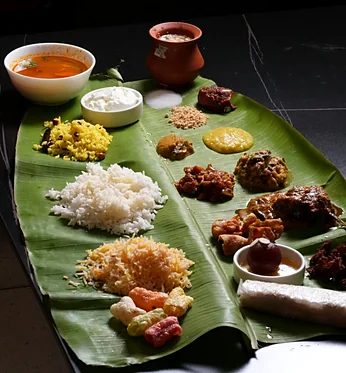 Banana-leaf thali with rice, curries, vegetable dishes, fried snacks and sweets