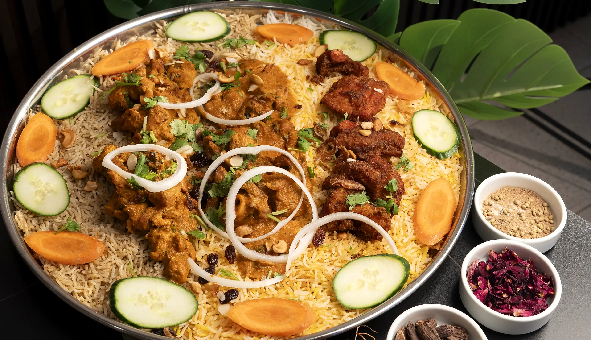 Mixed mandi platter: rice topped with spiced chicken pieces, onion rings, cucumber and carrot slices, with small bowls of whole spices