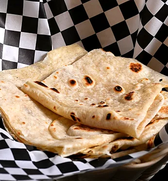 Stack of chapati in a checked paper-lined basket