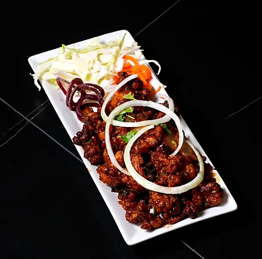 Crispy fried chicken pieces with onion rings, beetroot and cabbage on a long white platter