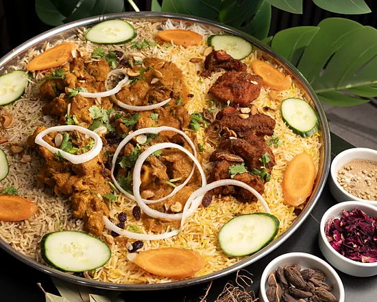 Mixed mandi platter: rice topped with spiced chicken pieces, onion rings, cucumber and carrot slices, with small bowls of whole spices